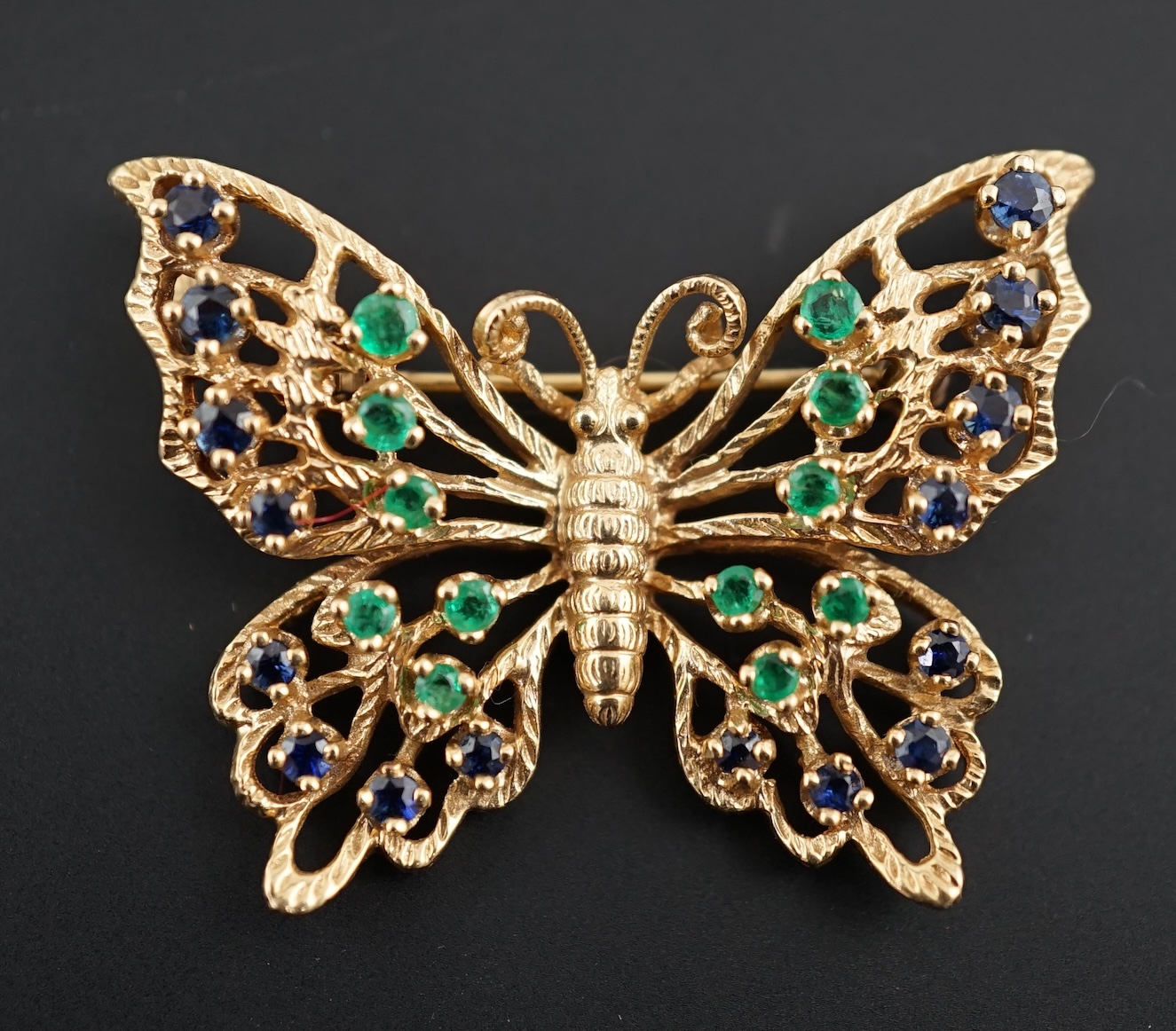 A modern pierced 14ct gold, emerald and sapphire cluster set butterfly brooch